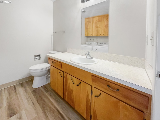 bathroom with vanity, toilet, washing machine and dryer, and hardwood / wood-style floors