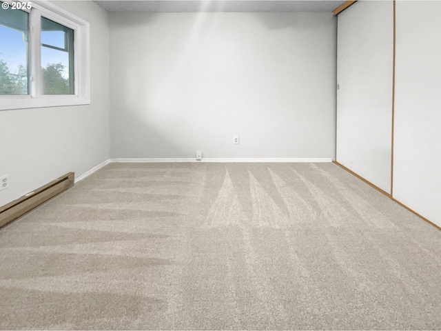 empty room featuring light colored carpet and a baseboard heating unit