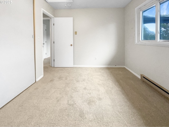 unfurnished room featuring light carpet and a baseboard heating unit