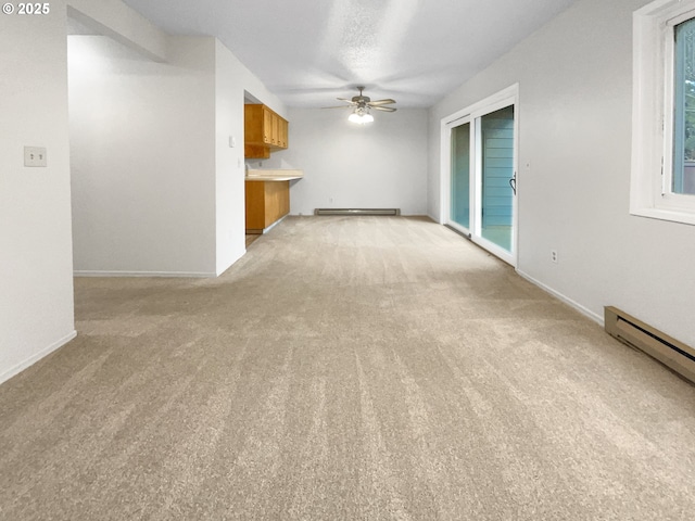 unfurnished living room with a baseboard heating unit, light colored carpet, and ceiling fan