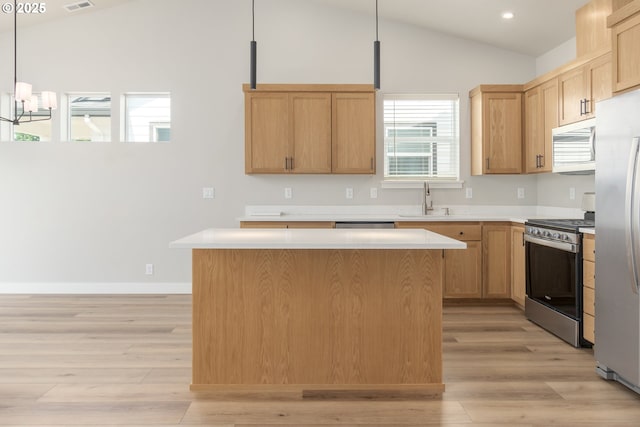 3237 Wildflower Dr, Springfield, OR 97478 - kitchen with stainless steel appliances, lofted ceiling, light wood-style floors, light countertops, and a kitchen island