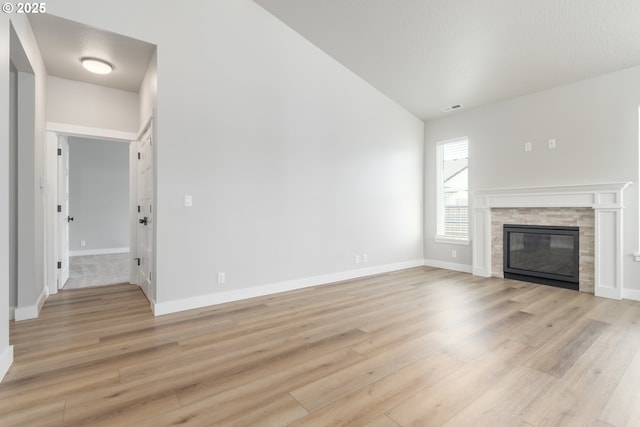 3237 Wildflower Dr, Springfield, OR 97478 - unfurnished living room featuring lofted ceiling, light wood finished floors, and a stone fireplace