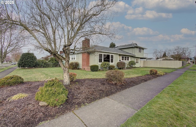 view of front of home with a chimney, a front lawn, and fence