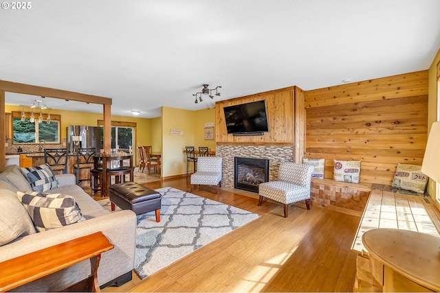 living area featuring wooden walls, wood finished floors, and a fireplace