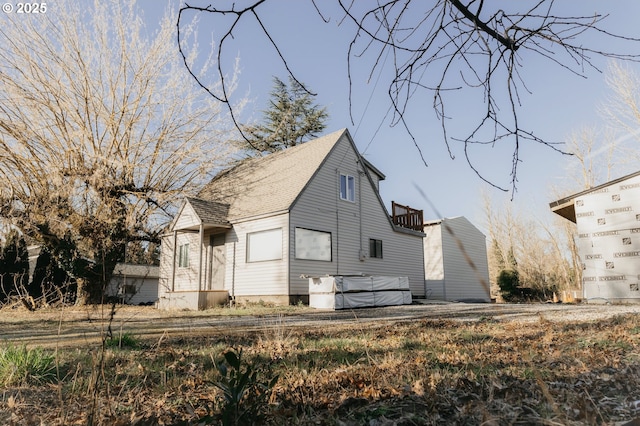 back of house with roof with shingles and a hot tub