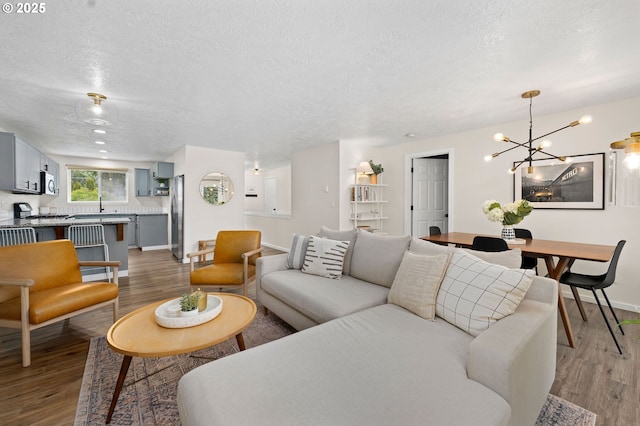 living room featuring hardwood / wood-style floors, a textured ceiling, and a notable chandelier