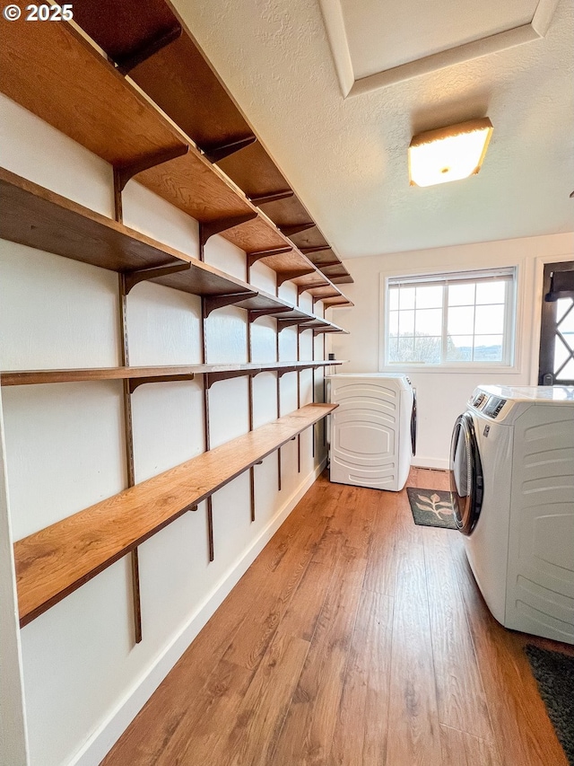washroom with separate washer and dryer, baseboards, wood finished floors, and laundry area