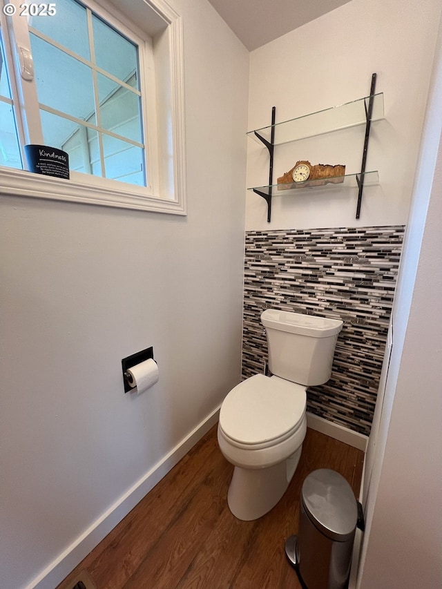 bathroom featuring plenty of natural light, toilet, wood finished floors, and tile walls