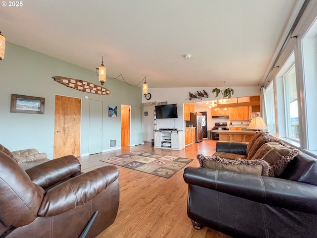 living area with vaulted ceiling, visible vents, and light wood-style flooring