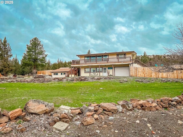 rear view of property with stairway, an attached garage, fence, a yard, and a wooden deck