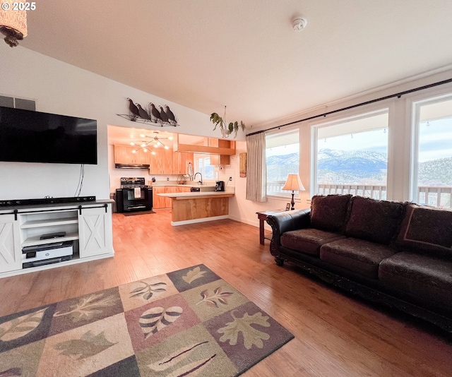 living room with baseboards, vaulted ceiling, and light wood-style flooring