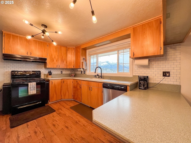 kitchen featuring under cabinet range hood, stainless steel dishwasher, a sink, a textured ceiling, and black electric range oven