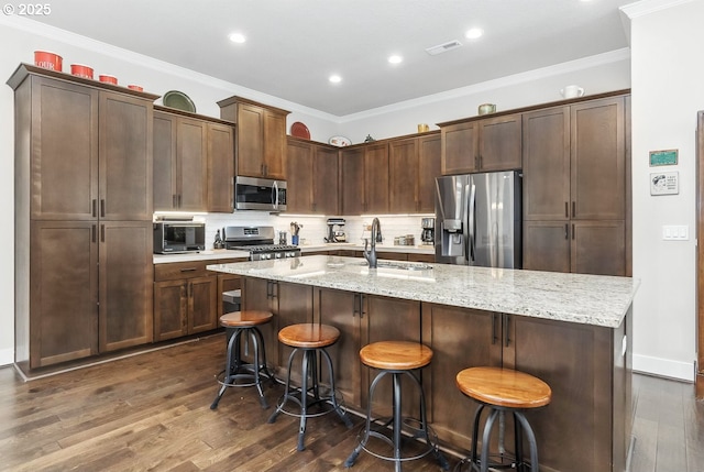 16949 SW Appledale Rd, Beaverton, OR 97007 - kitchen featuring appliances with stainless steel finishes, dark wood-type flooring, a kitchen island with sink, tasteful backsplash, and crown molding