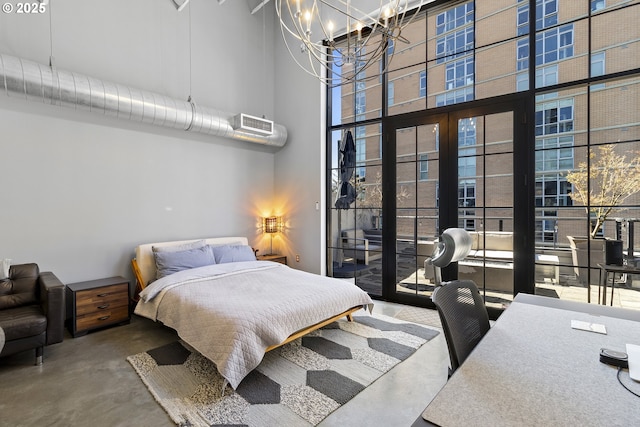 bedroom with a towering ceiling, concrete flooring, a chandelier, and access to outside