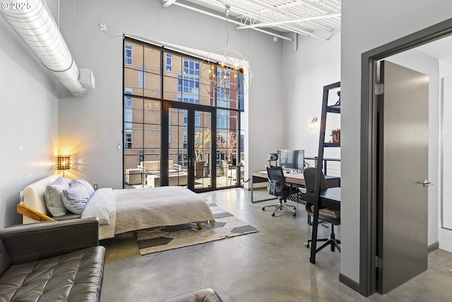 bedroom with a notable chandelier, a towering ceiling, concrete floors, and french doors