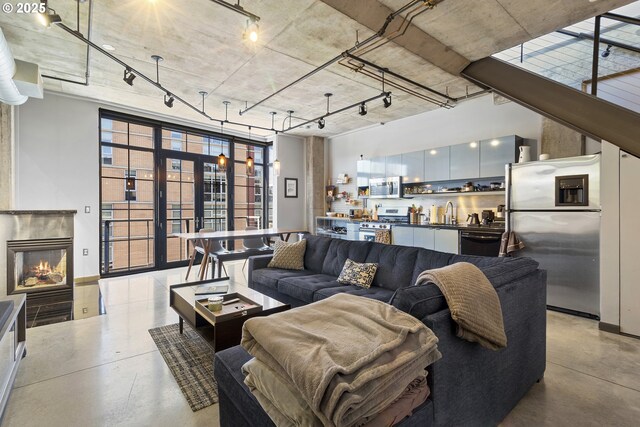 living room featuring sink, a towering ceiling, rail lighting, and french doors