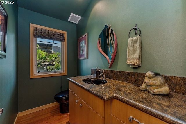 bathroom with visible vents, baseboards, toilet, wood finished floors, and vanity