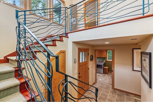 stairway with tile patterned flooring, washer / dryer, baseboards, and a towering ceiling