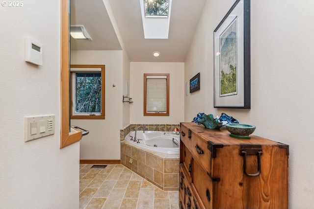 full bath featuring vanity, visible vents, baseboards, a skylight, and a jetted tub