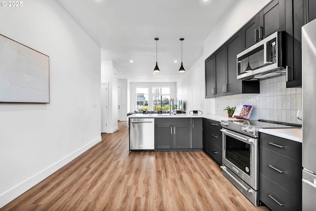 kitchen featuring sink, hanging light fixtures, tasteful backsplash, kitchen peninsula, and appliances with stainless steel finishes