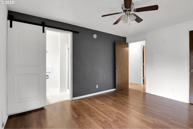 4021 N Clarey St, Eugene, OR 97402 - unfurnished bedroom with wood finished floors, a barn door, a ceiling fan, and baseboards