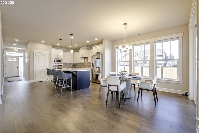 dining area featuring dark wood-type flooring, sink, and a notable chandelier