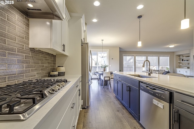 kitchen featuring pendant lighting, stainless steel appliances, sink, and white cabinets