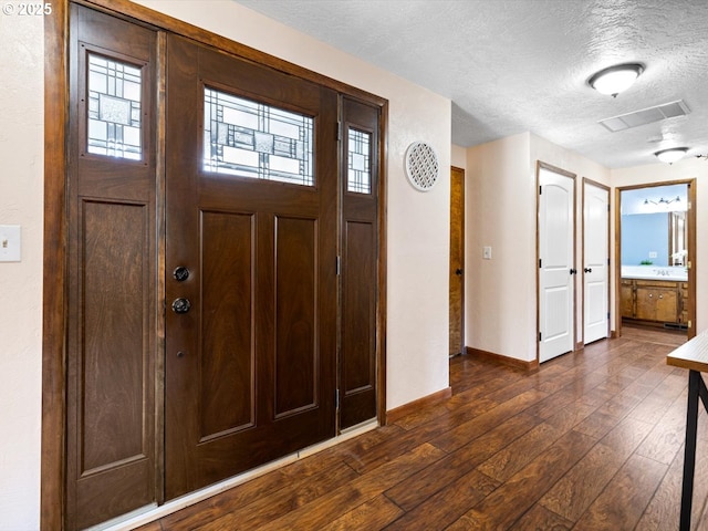 entryway with dark wood-type flooring and a textured ceiling