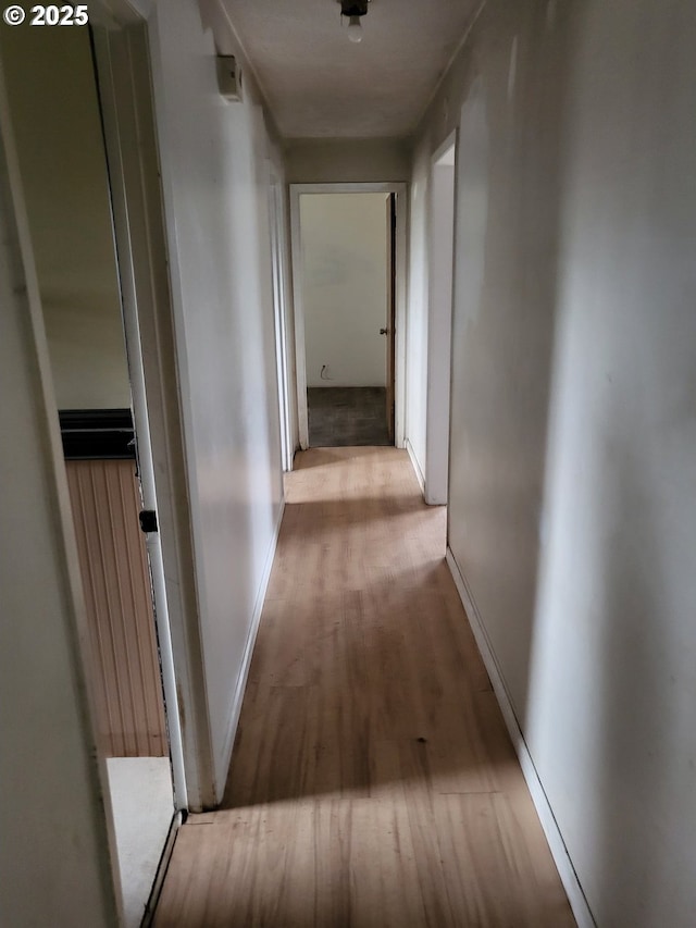 corridor featuring wood finished floors and baseboards