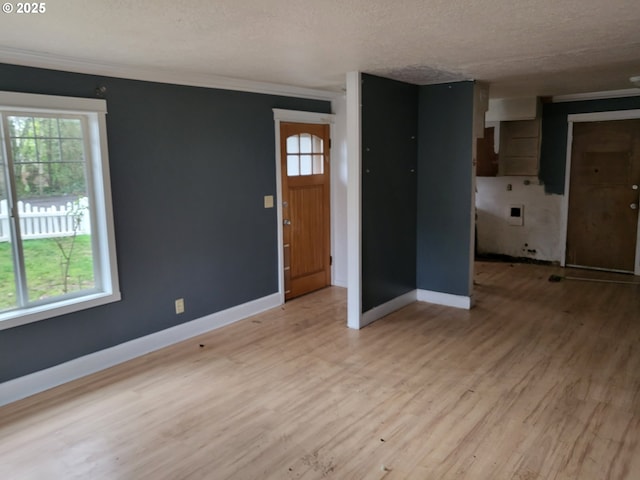 unfurnished living room with ornamental molding, baseboards, light wood-type flooring, and a textured ceiling