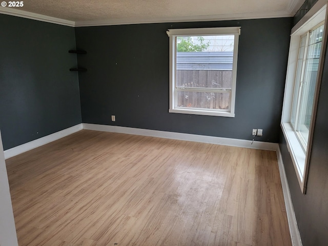 spare room featuring baseboards, a textured ceiling, wood finished floors, and crown molding