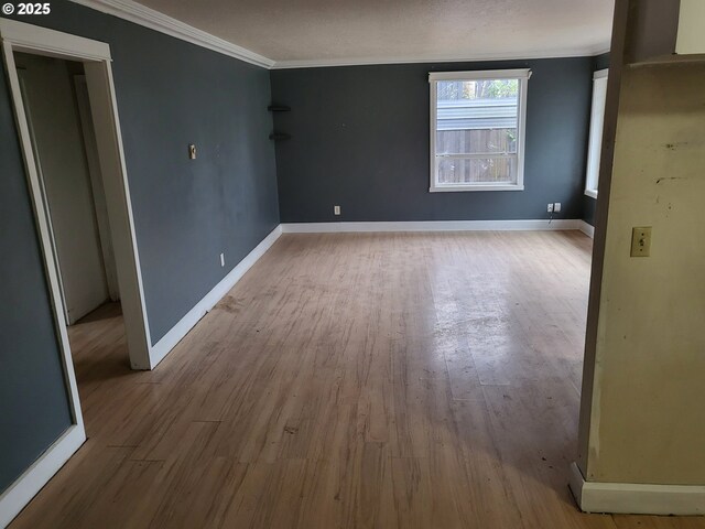 empty room featuring crown molding, wood finished floors, and baseboards