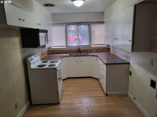 kitchen featuring light wood-style flooring, a sink, dark countertops, a textured ceiling, and white electric range oven