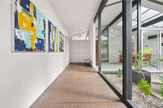 hallway featuring baseboards, speckled floor, and lofted ceiling