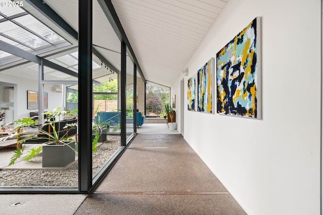 hall with baseboards, a wall mounted air conditioner, speckled floor, and lofted ceiling