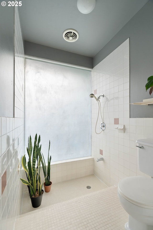 full bathroom with visible vents, tile walls, tile patterned flooring, toilet, and tiled shower