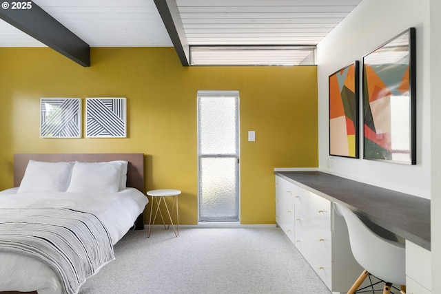bedroom with built in study area, carpet, baseboards, and beamed ceiling