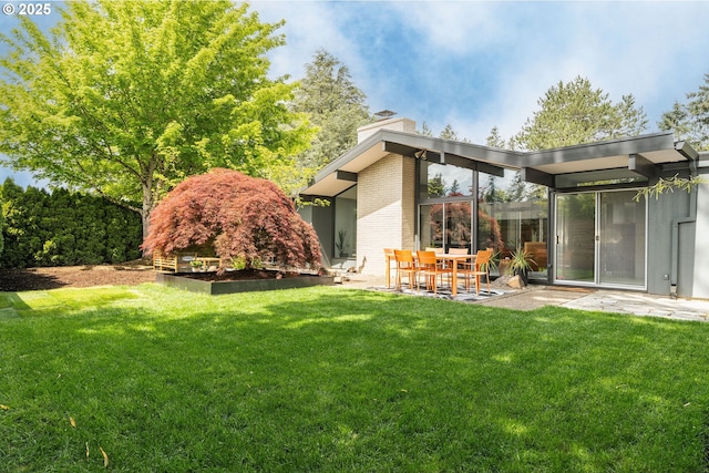 rear view of property with a lawn, a patio, and a chimney