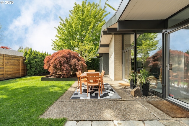 view of yard featuring a patio, fence, and outdoor dining space