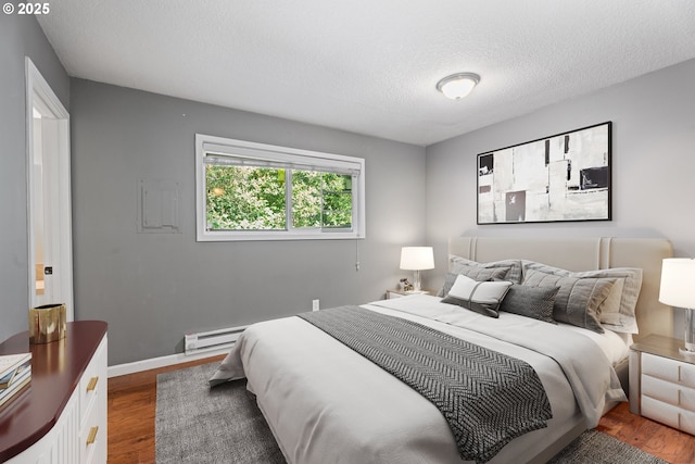 11255 SW Springwood Dr, Portland, OR 97223 - bedroom featuring a baseboard radiator, dark wood finished floors, and a textured ceiling
