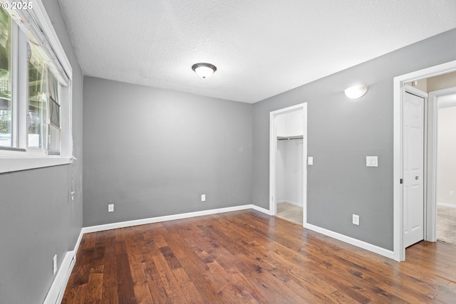 11255 SW Springwood Dr, Portland, OR 97223 - unfurnished bedroom with wood finished floors, a textured ceiling, a closet, and a walk in closet