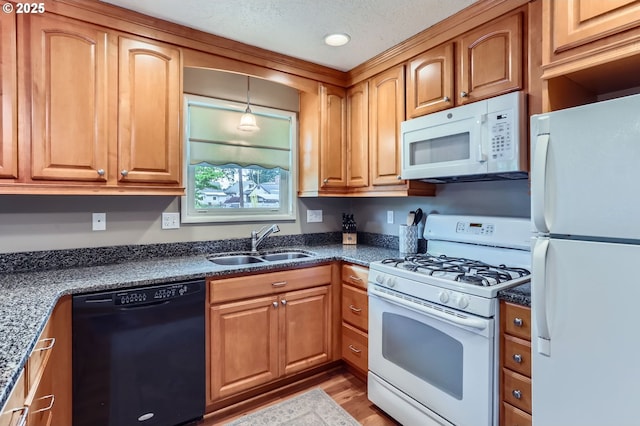 157 NE 11th Dr, Hillsboro, OR 97124 - kitchen featuring white appliances, a sink, light wood-type flooring, brown cabinetry, and hanging light fixtures