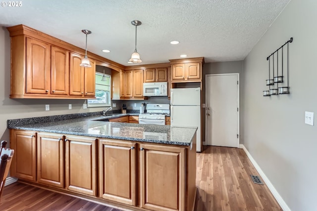 157 NE 11th Dr, Hillsboro, OR 97124 - kitchen featuring white appliances, a peninsula, dark stone countertops, wood finished floors, and recessed lighting