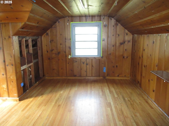 additional living space featuring lofted ceiling, wooden walls, and hardwood / wood-style flooring