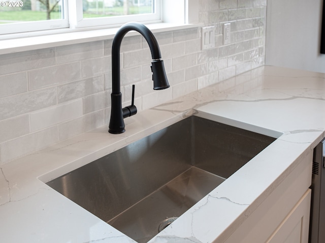 interior details featuring light stone counters, tasteful backsplash, and a sink