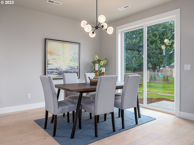 dining room with baseboards, light wood-style floors, visible vents, and a chandelier