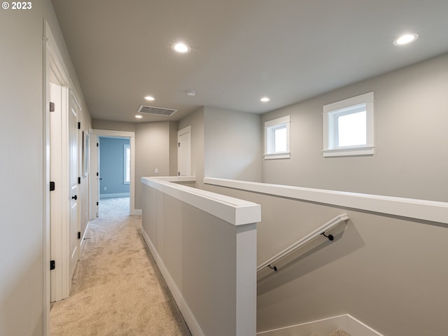 hallway with visible vents, an upstairs landing, recessed lighting, baseboards, and light colored carpet