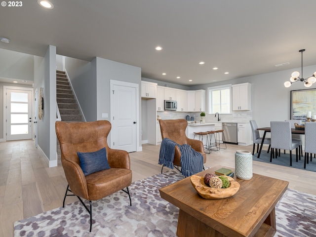 living area with a chandelier, stairway, light wood-style flooring, and recessed lighting