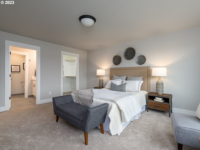 bedroom featuring carpet, baseboards, ensuite bath, a spacious closet, and a closet