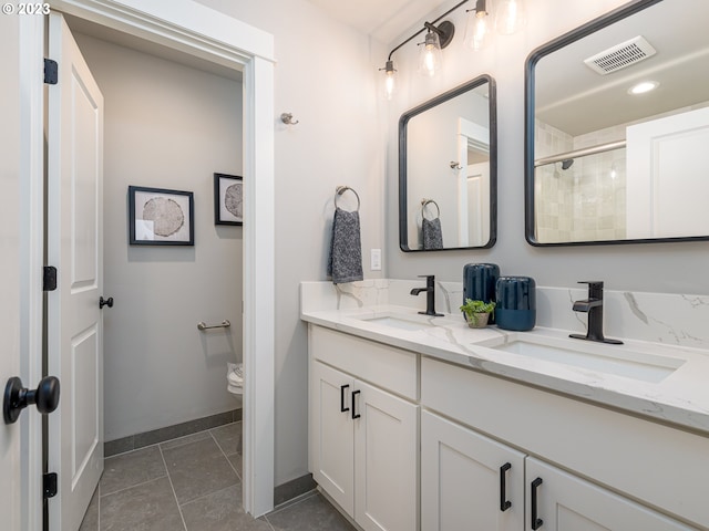 bathroom featuring a sink, visible vents, double vanity, and tile patterned flooring